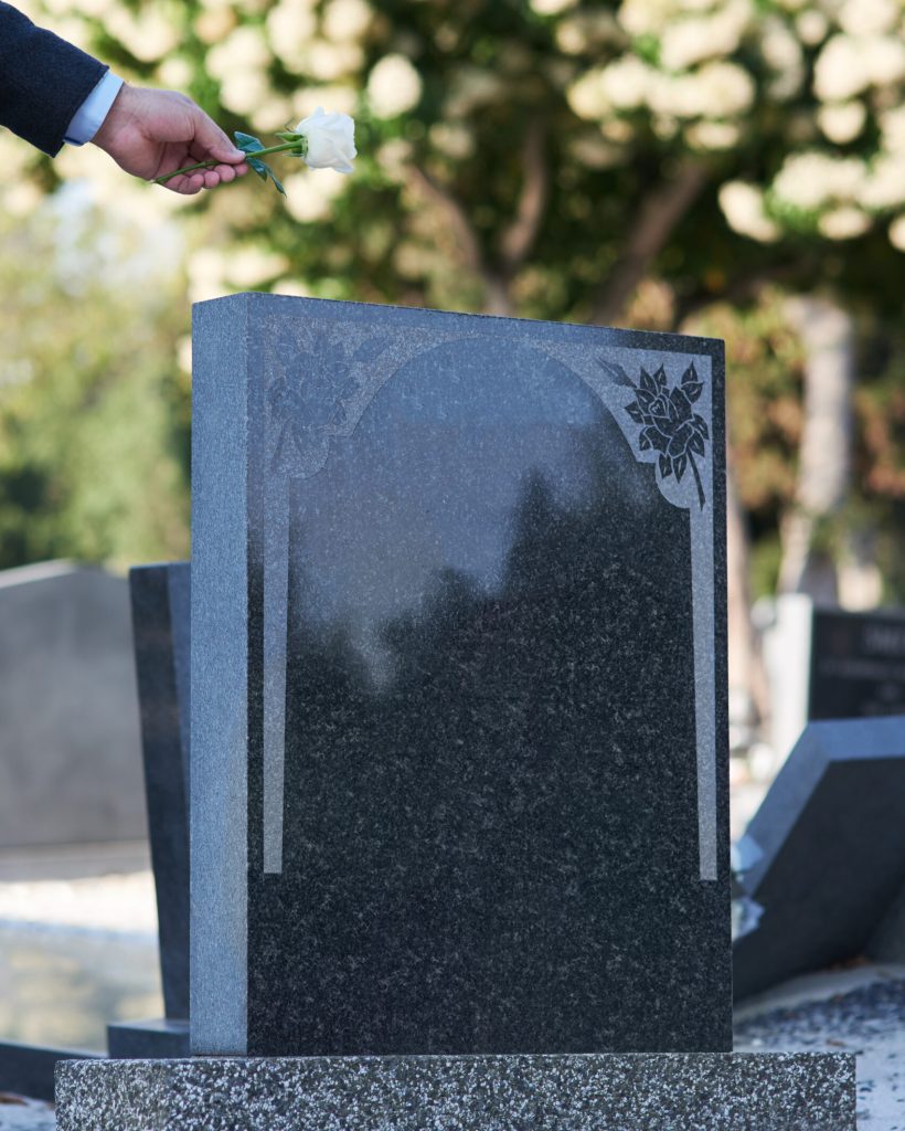 The final goodbye. Cropped shot of a man placing a white rose on a grave The final goodbye. Cropped shot of a man placing a white rose on a grave