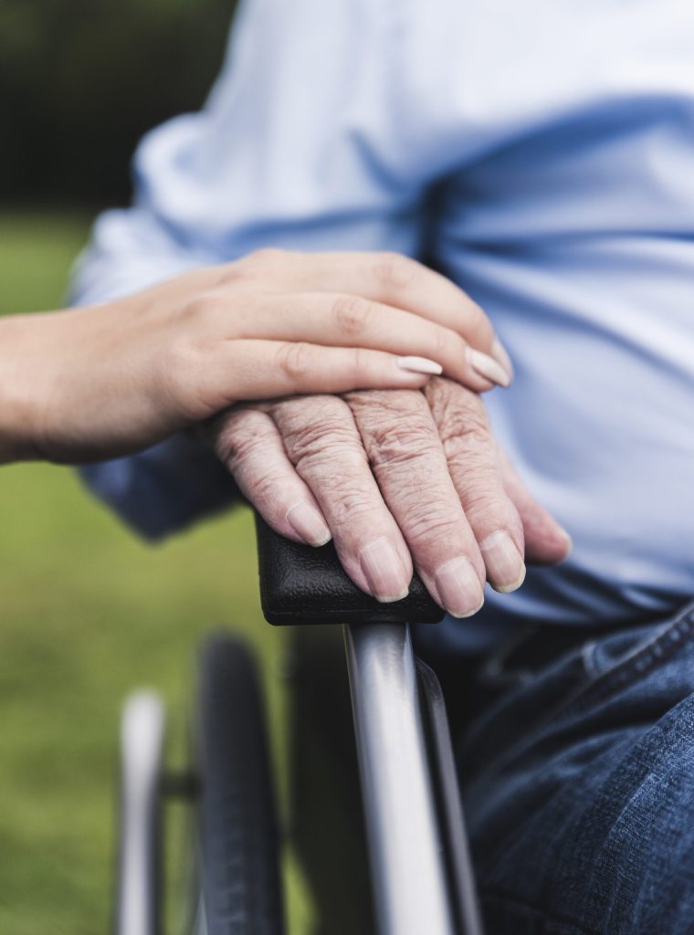 Young woman touching senior man’s hand, close-up Young woman touching senior man's hand, close-up